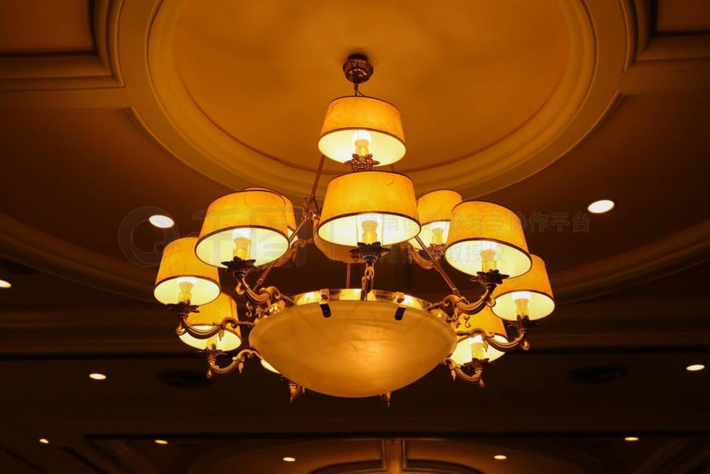 Yellow lamps with brass structure on ceiling in ballroom