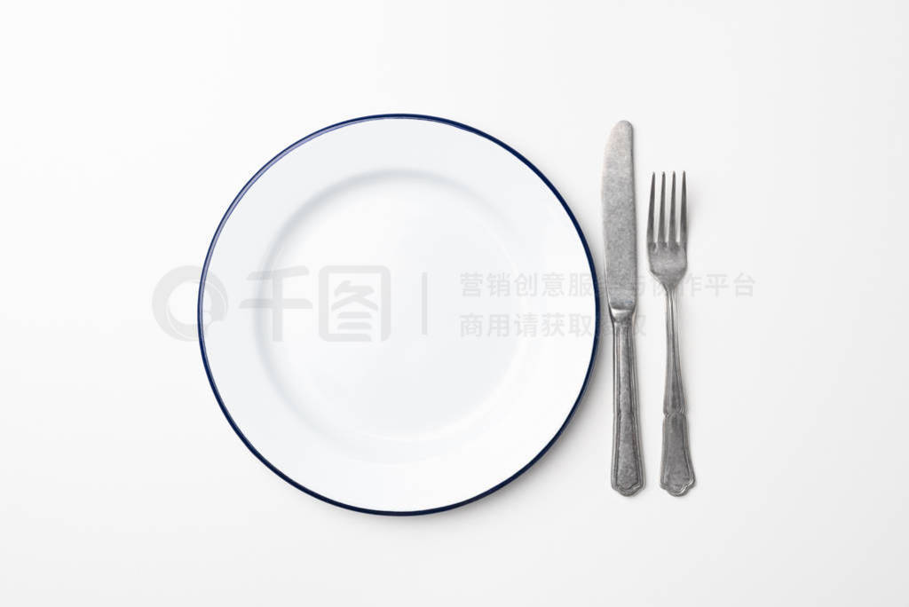 Empty plate and cutlery on white background