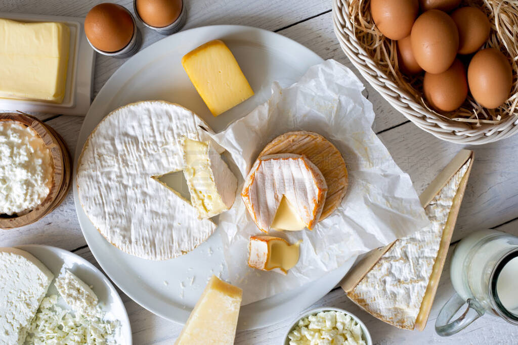 Cheese, milk, dairy products and eggs on rustic white wood from