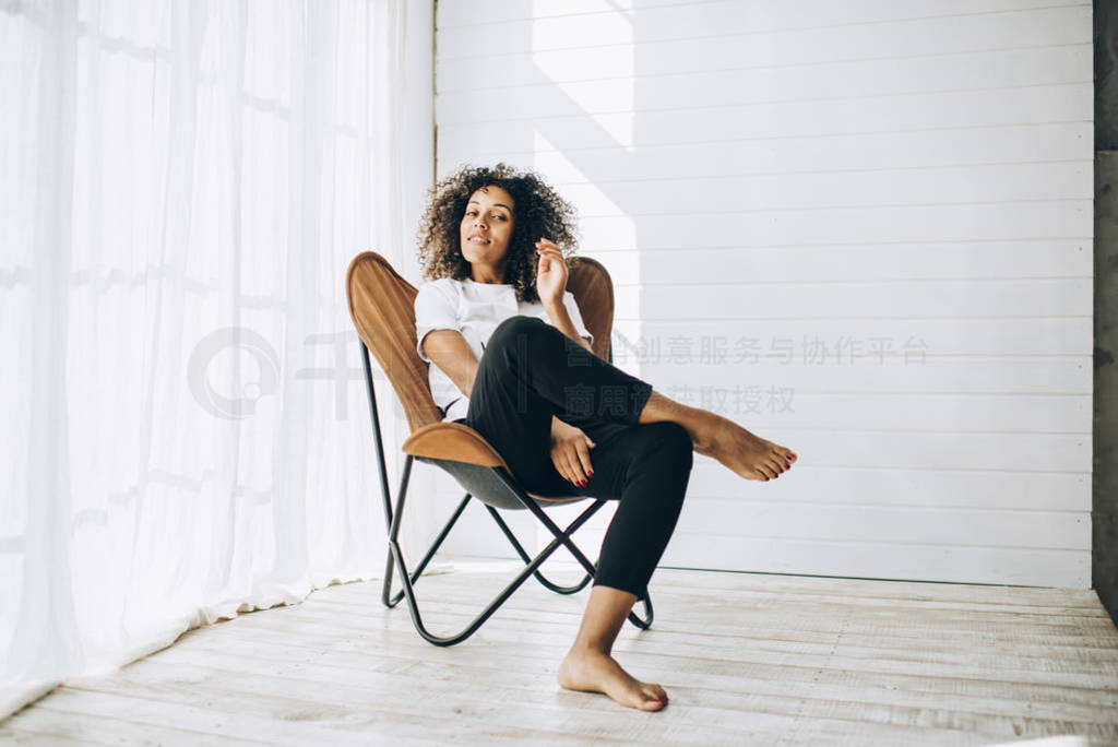 Beautiful ethnic woman sitting in armchair