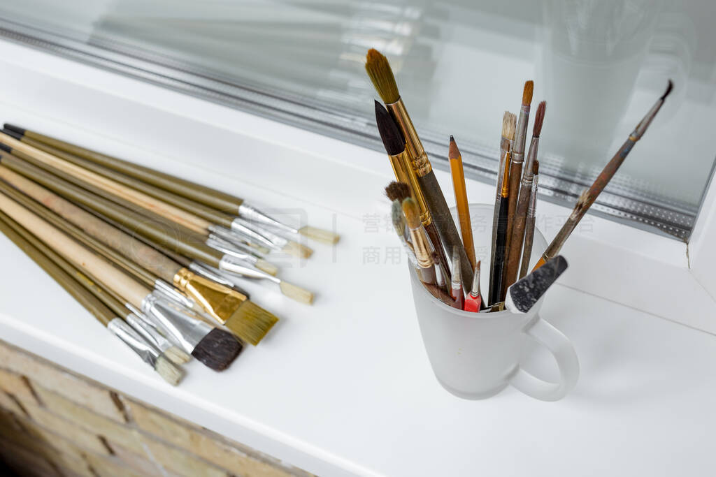 Brushes for painting on the white windowsill and brushes on a gl