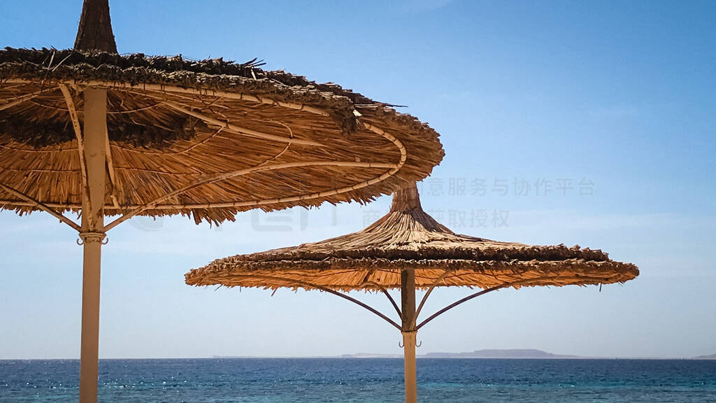 symmetrical thatched beach umbrellas on a sultry summer day.