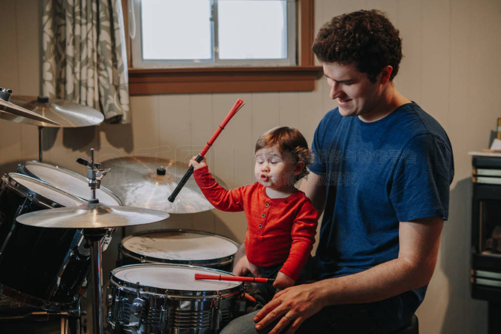 Father teaching baby boy to play drums. Parent with toddler chil