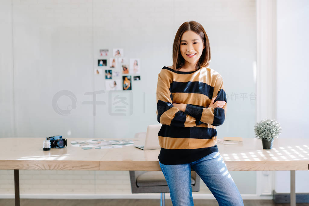 Portrait of smiling Asian woman photographer standing with arms