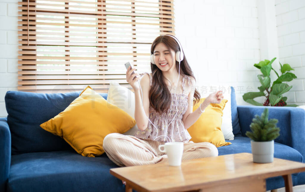 Teenager Asian girl sitting on the sofa listening to music with