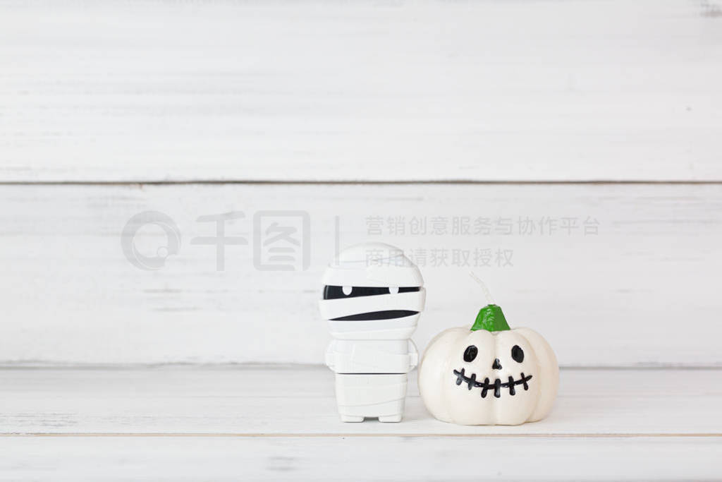 White candle pumpkin with mummy on white wooden background with