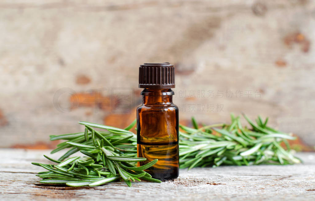 Small bottle of essential rosemary oil on the old wooden backgro