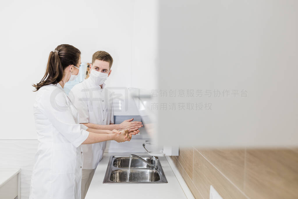 Two doctors wash their hands in protective medical masks during
