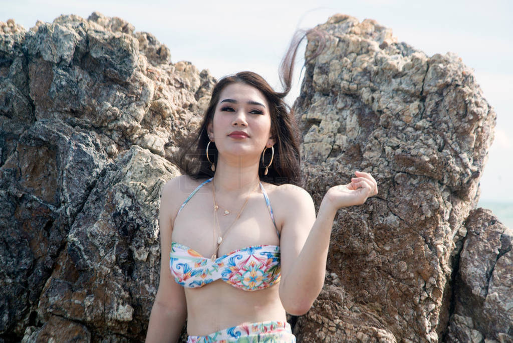 Portrait of pretty Asian female in a white swimming suit standin