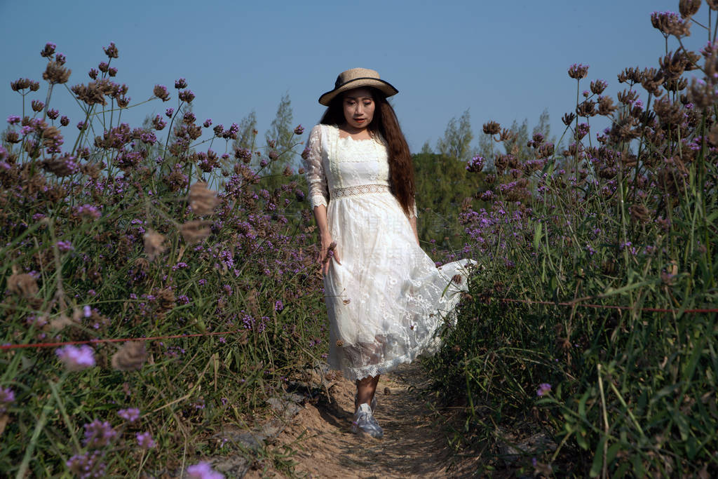 Asian pretty woman standing in a verbina bonariensis flower gard