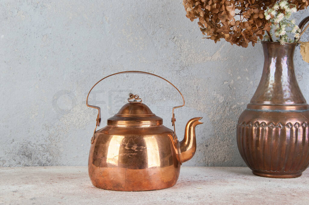 Vintage copper teapot on concrete background.