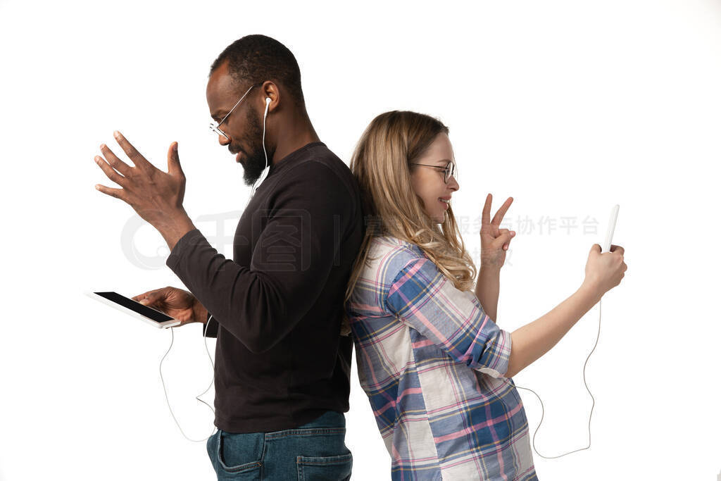 Emotional man and woman using gadgets on white studio background