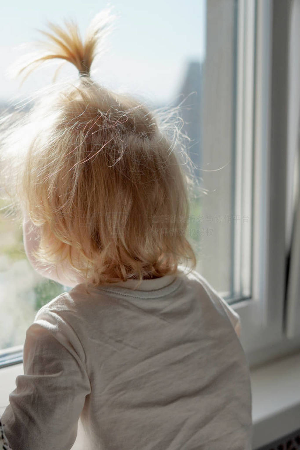 Two-year-old blond child with a funny haircut on his head looks