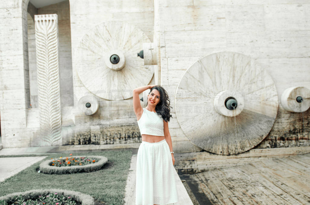 young woman in white dress outside posing and smiling