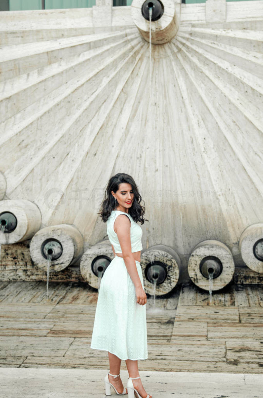 young woman in white dress outside posing and smiling