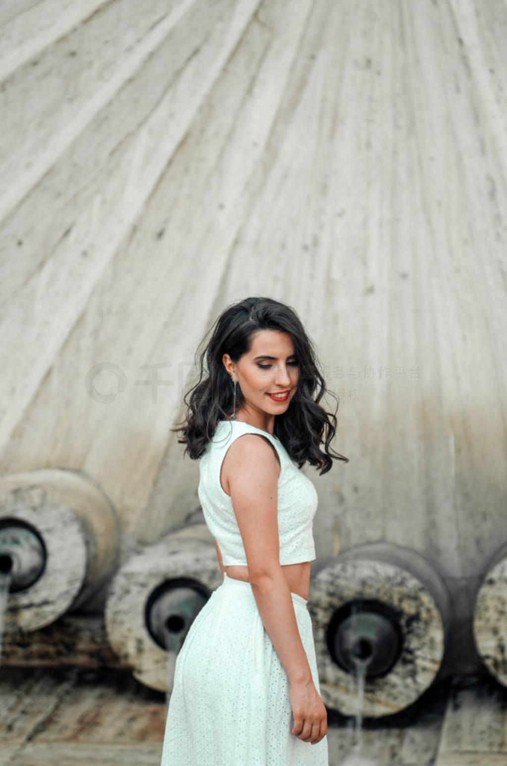 young woman in white dress outside posing and smiling