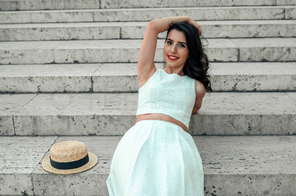 young woman in white dress outside posing and smiling