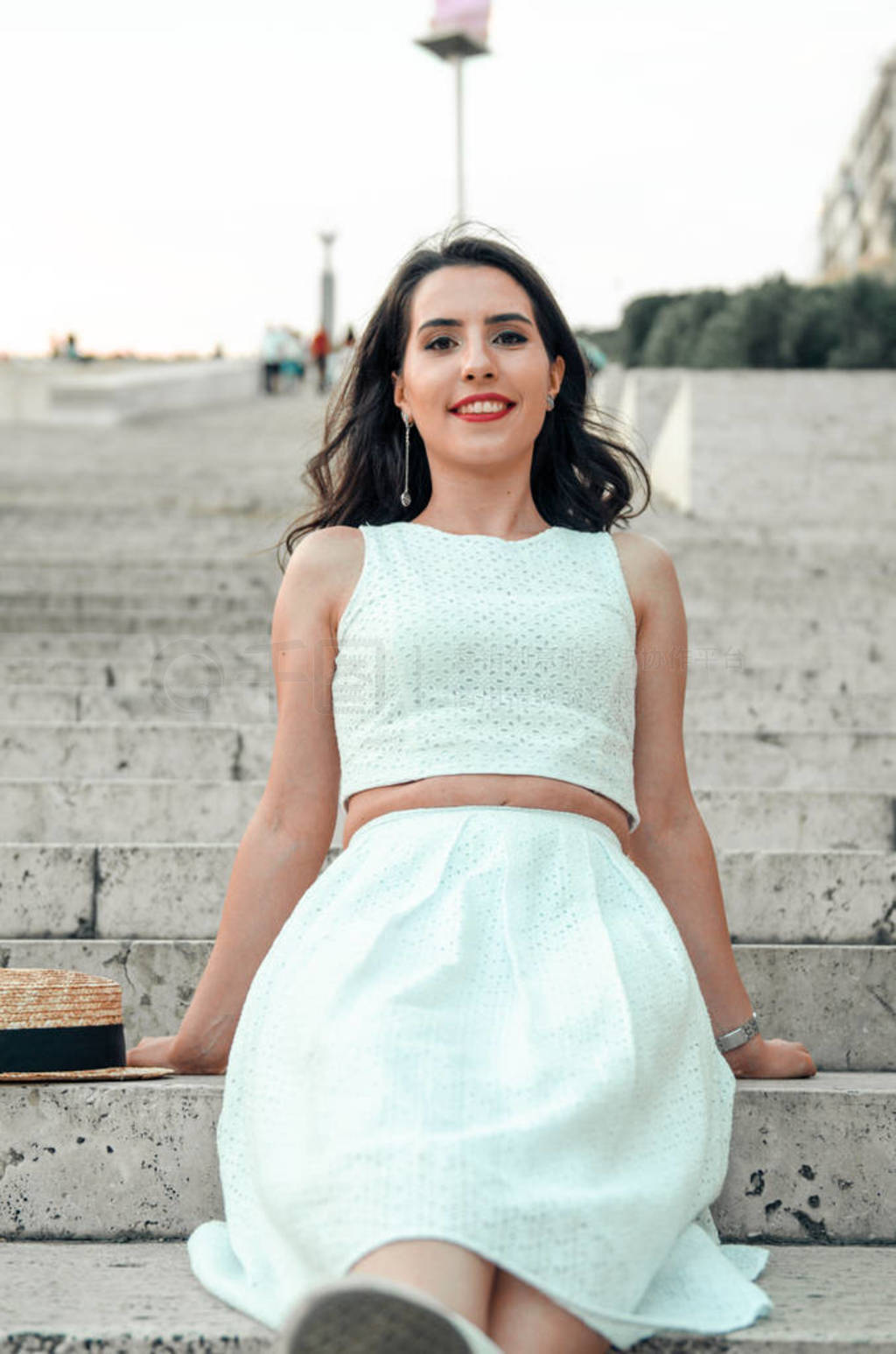 young woman in white dress outside posing and smiling