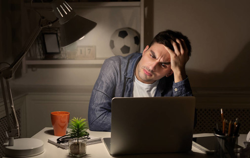 疲惫的人在家工作到深夜在笔记本电脑上