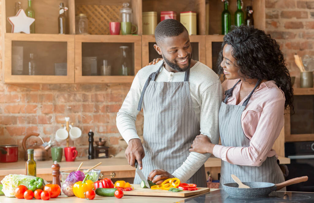 Emotional african couple cooking dinner together in kitchen