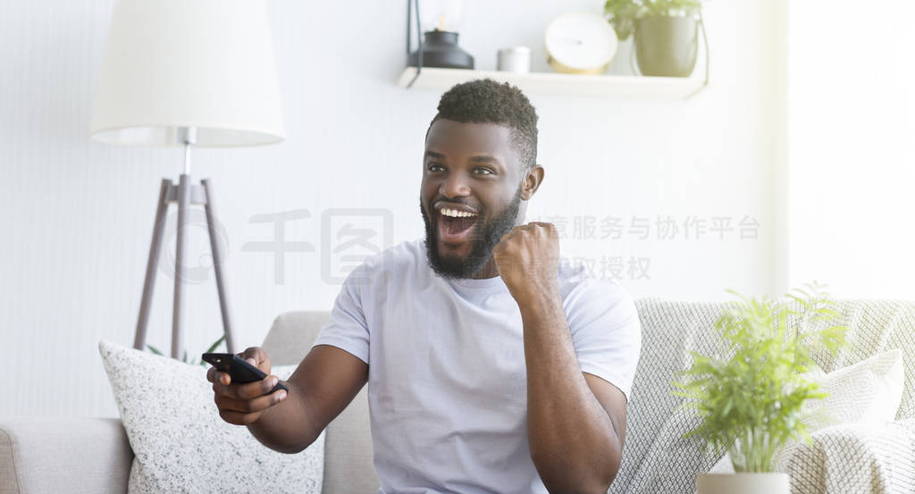 Emotional african soccer fan watching football on tv at home