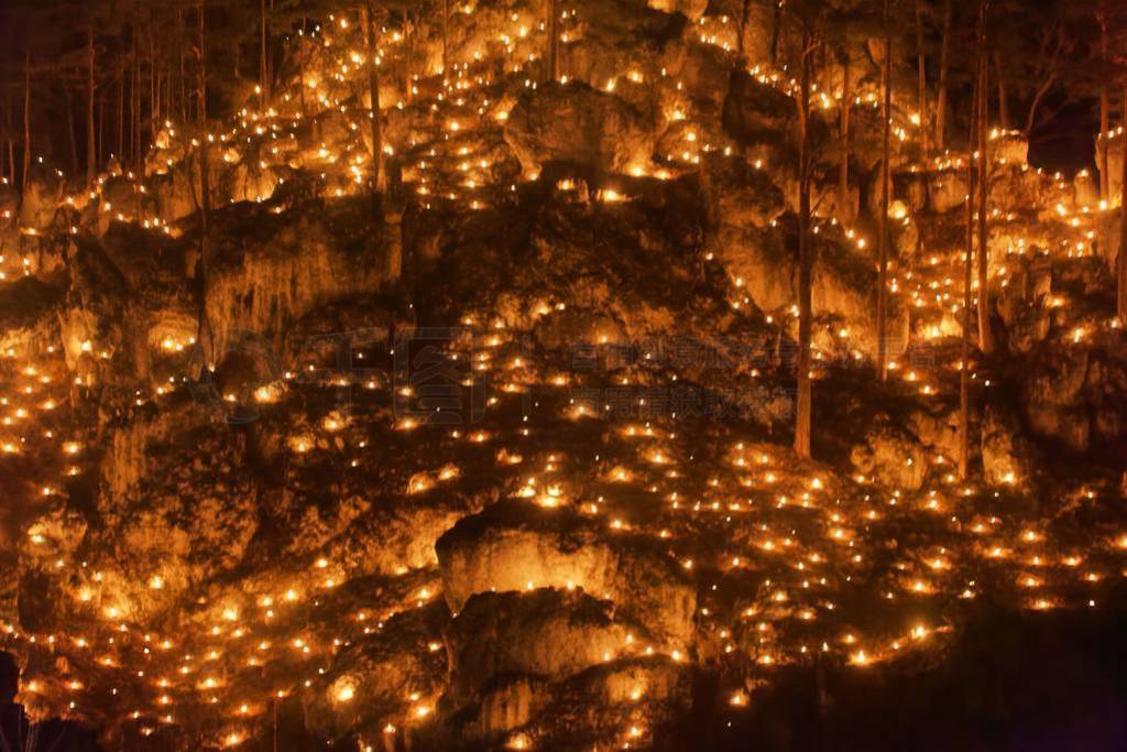 Small fires in a rocky hill with trees during a light celebratio