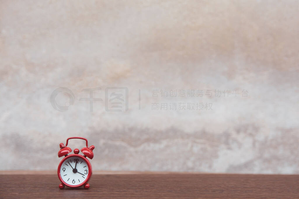 Red alarm clock on table dark plank wooden background with copy