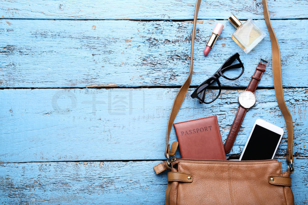 Handbag with cosmetics, smartphone, passport and wrist watch on