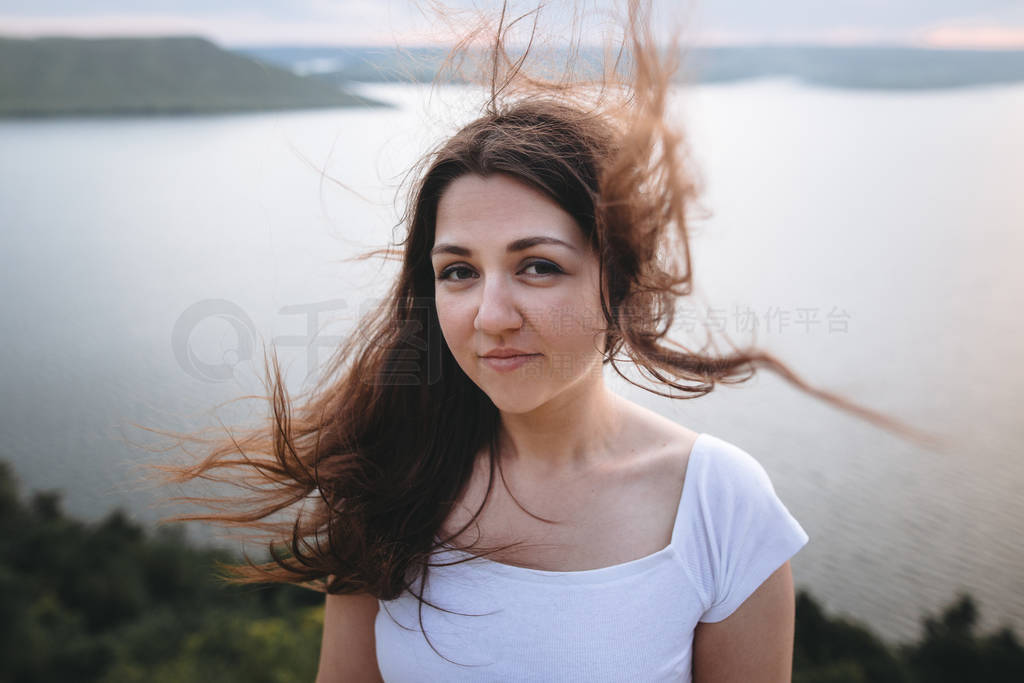Traveler girl with windy hair relaxing on top of rock mountain,