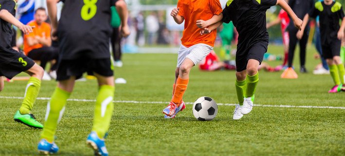年轻的男孩儿童在玩青年足球足球游戏锦标赛的制服。横向运动背景