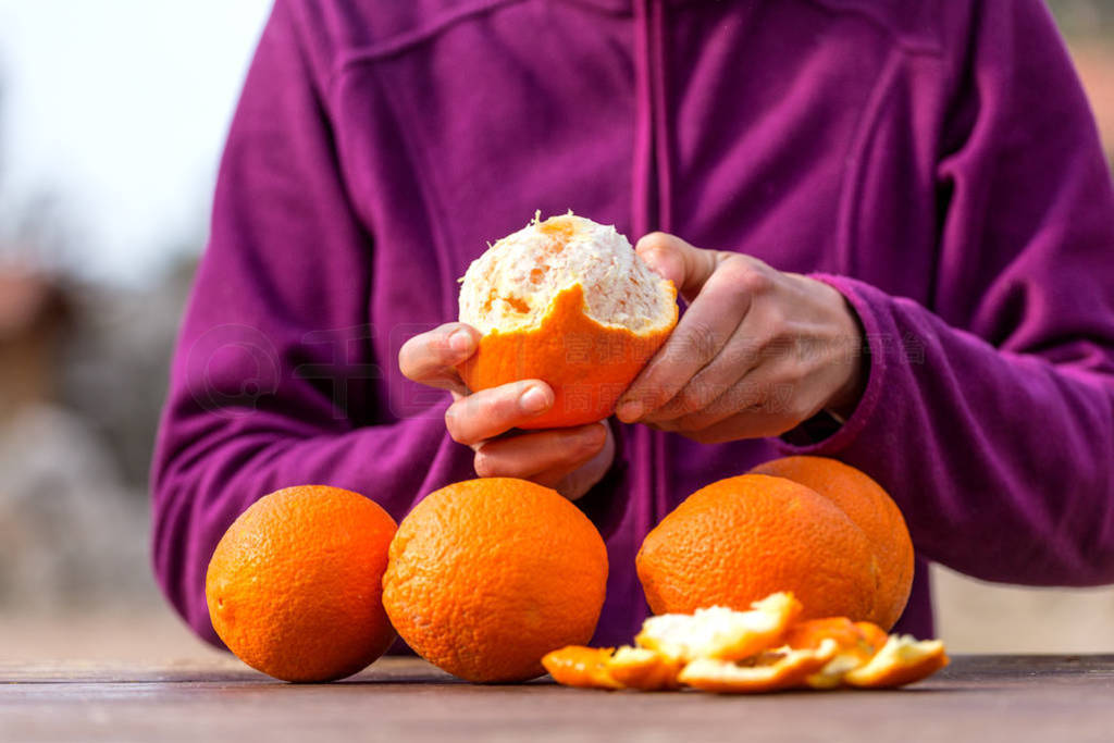 Woman peels oranges from peel.