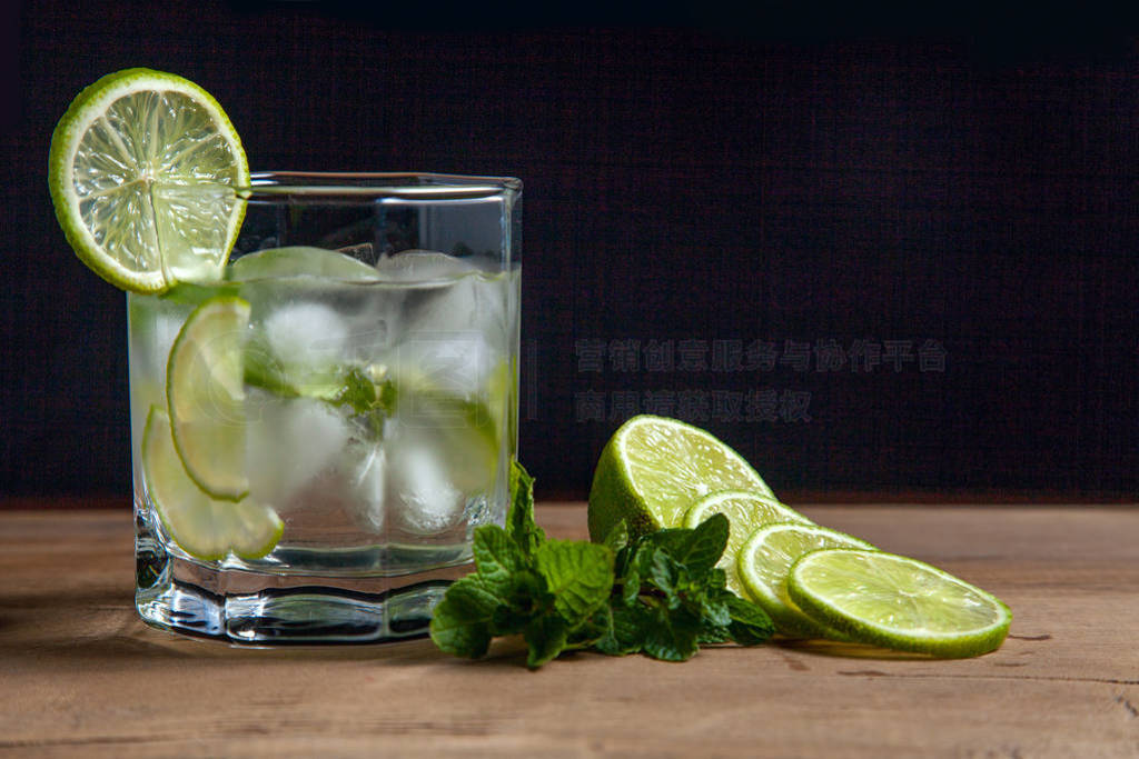 Summer cocktail mojito in glass, sliced lime and mint on wooden