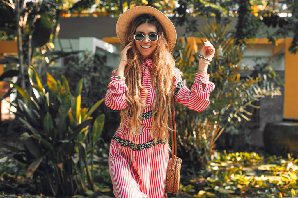 cheerful young fashionable woman in hat having fun outdoors