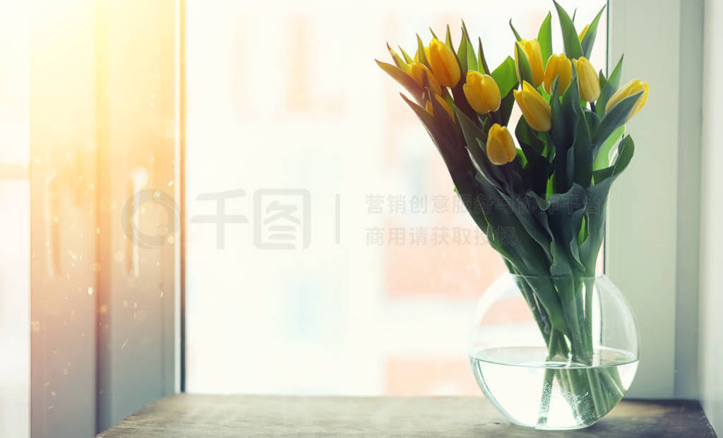A bouquet of red tulips in a vase on the windowsill. A gift for