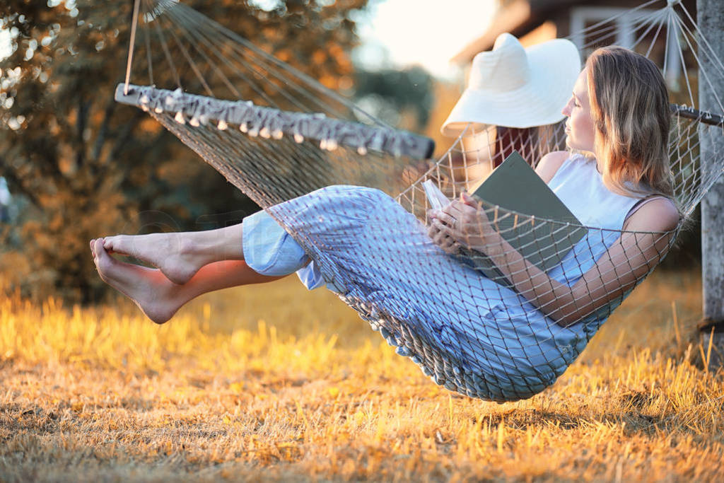 Beautiful girl in hammock reading a book