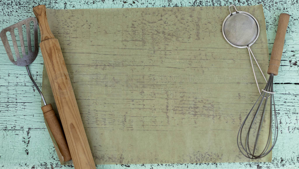 Vintage old kitchen utensils on a green wooden background.