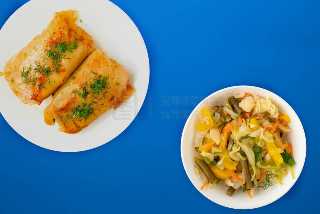 cabbage rolls in a white plate with vegetable salad and sauce.