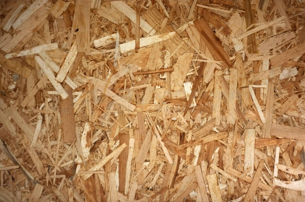 OSB Boards or brown wood chips sanded into a wooden background.