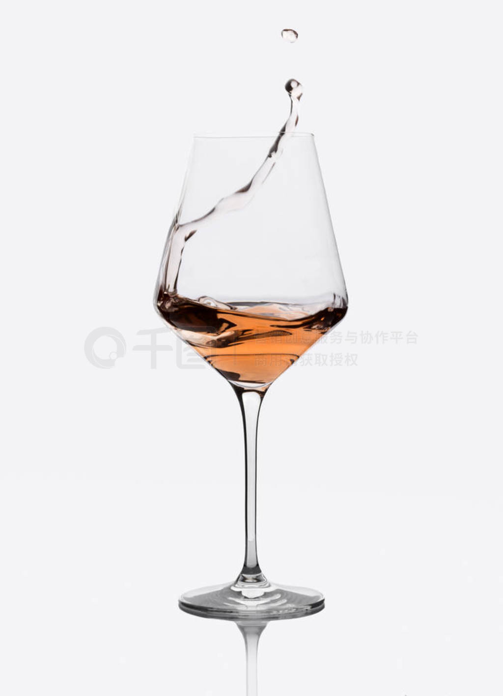 Glass of amber wine with splashes isolated on white.