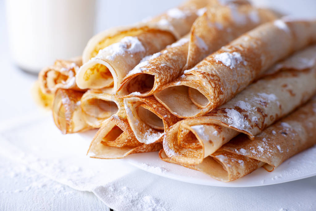 Fried pancakes rolled into a tube on a white plate.