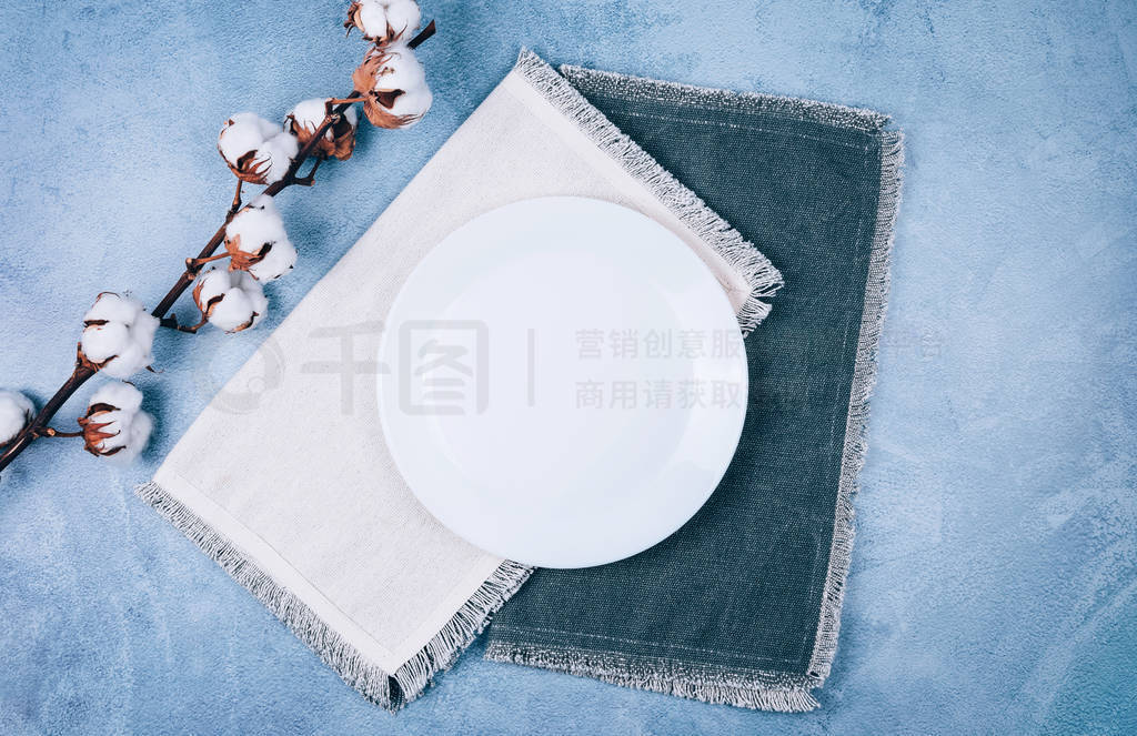 Empty circle plate on linen napkins decorated with cotton flower