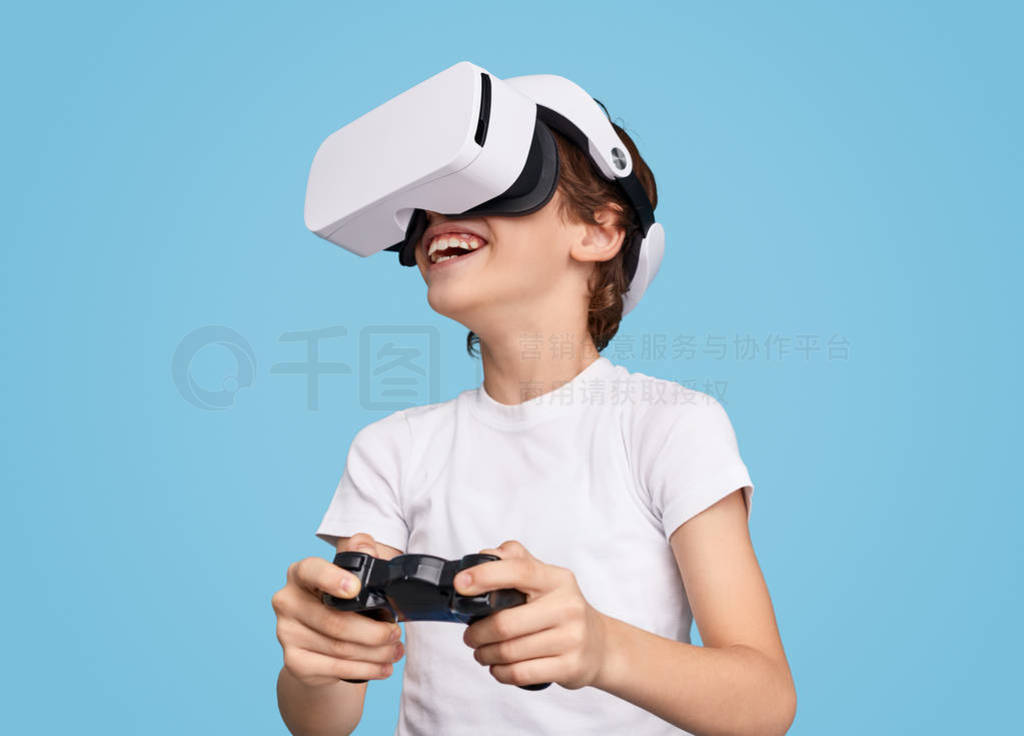 Cheerful boy playing videogame in VR goggles