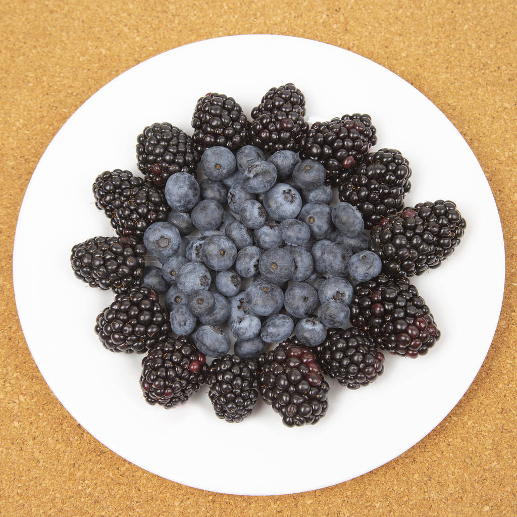 Blueberries and blackberries on a white plate. Vitamin and Diet