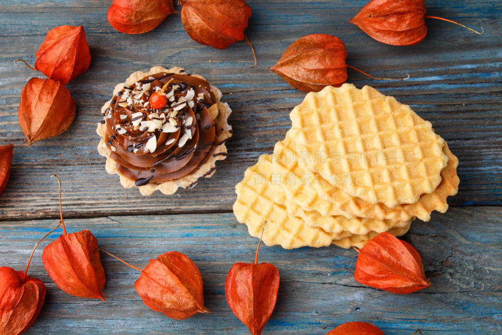 Sweet waffle, cake with cream and physalis on a wooden backgr