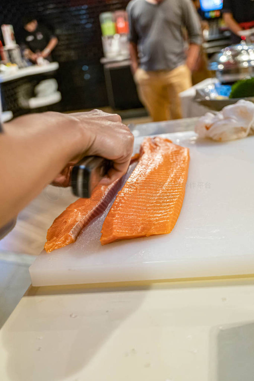 Chef preparing and cutting fresh salmon in Japanese restaurant