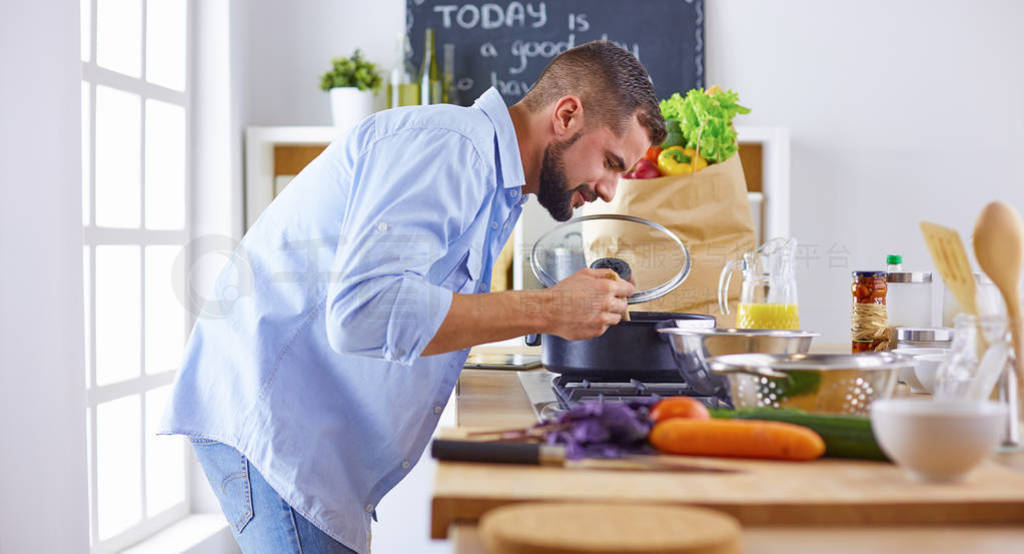 Smiling and confident chef standing in a large kitchen tasting