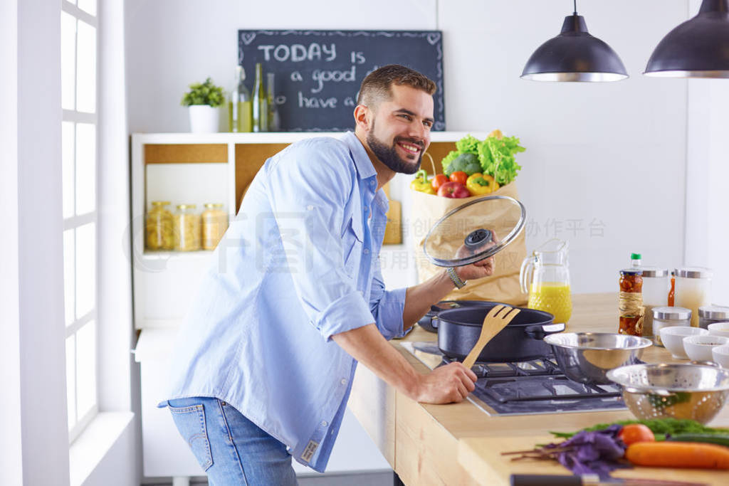 Smiling and confident chef standing in a large kitchen tasting