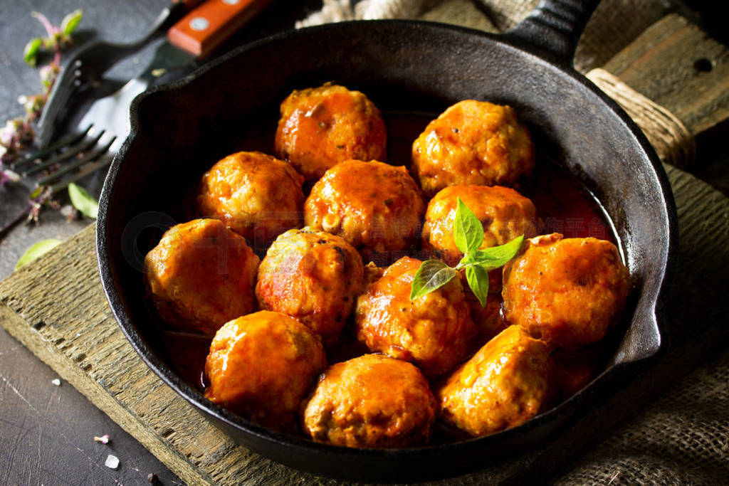 Homemade Beef meatballs in tomato sauce in a frying pan on dark