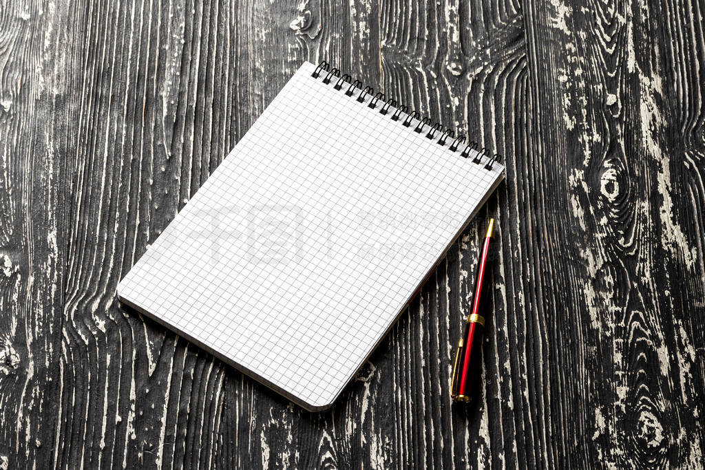 The notebook with squared pages and pen on a black table with a