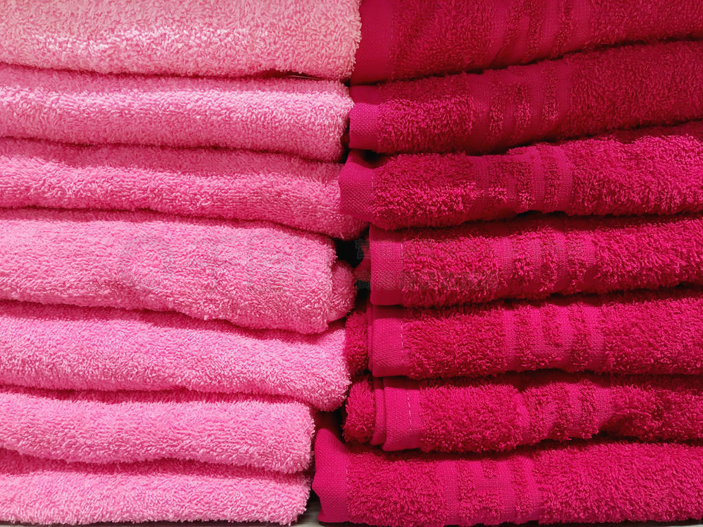Stack of pink and red terry towels. Pile of textile bath accesso